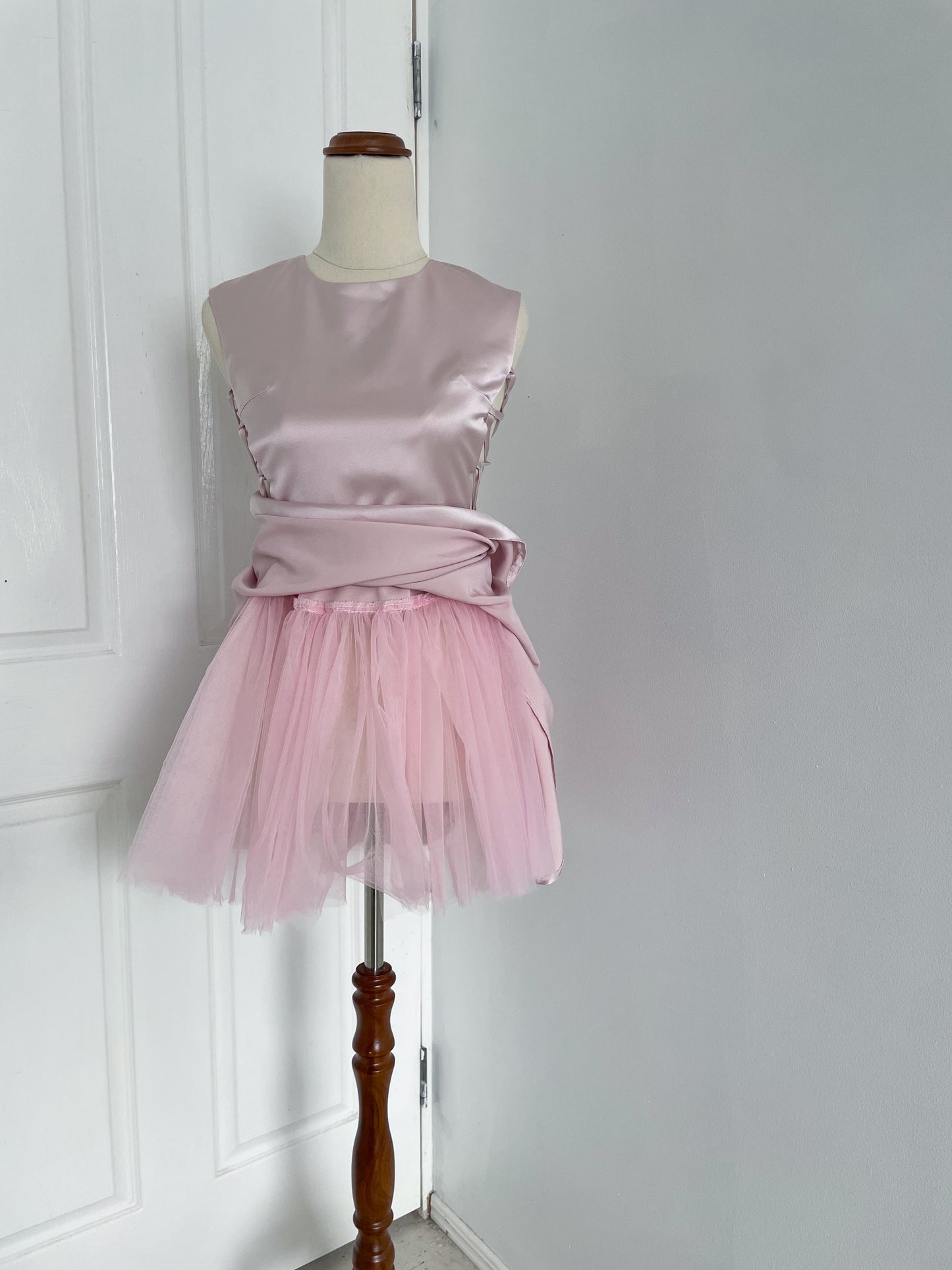 of A pink ballerina inspired mini dress with corset sides showing in-built tutu
