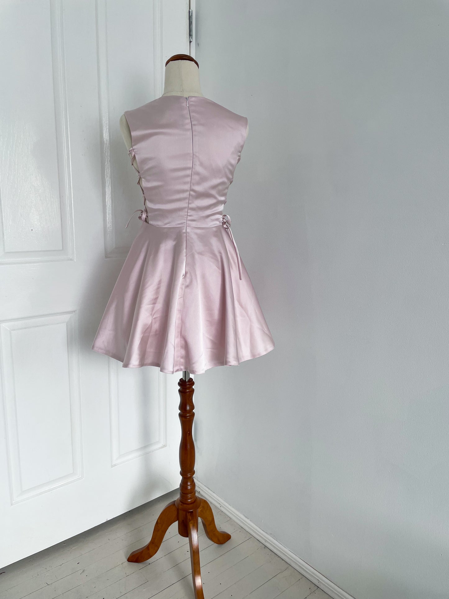 back view of of A pink ballerina inspired mini dress with corset sides
