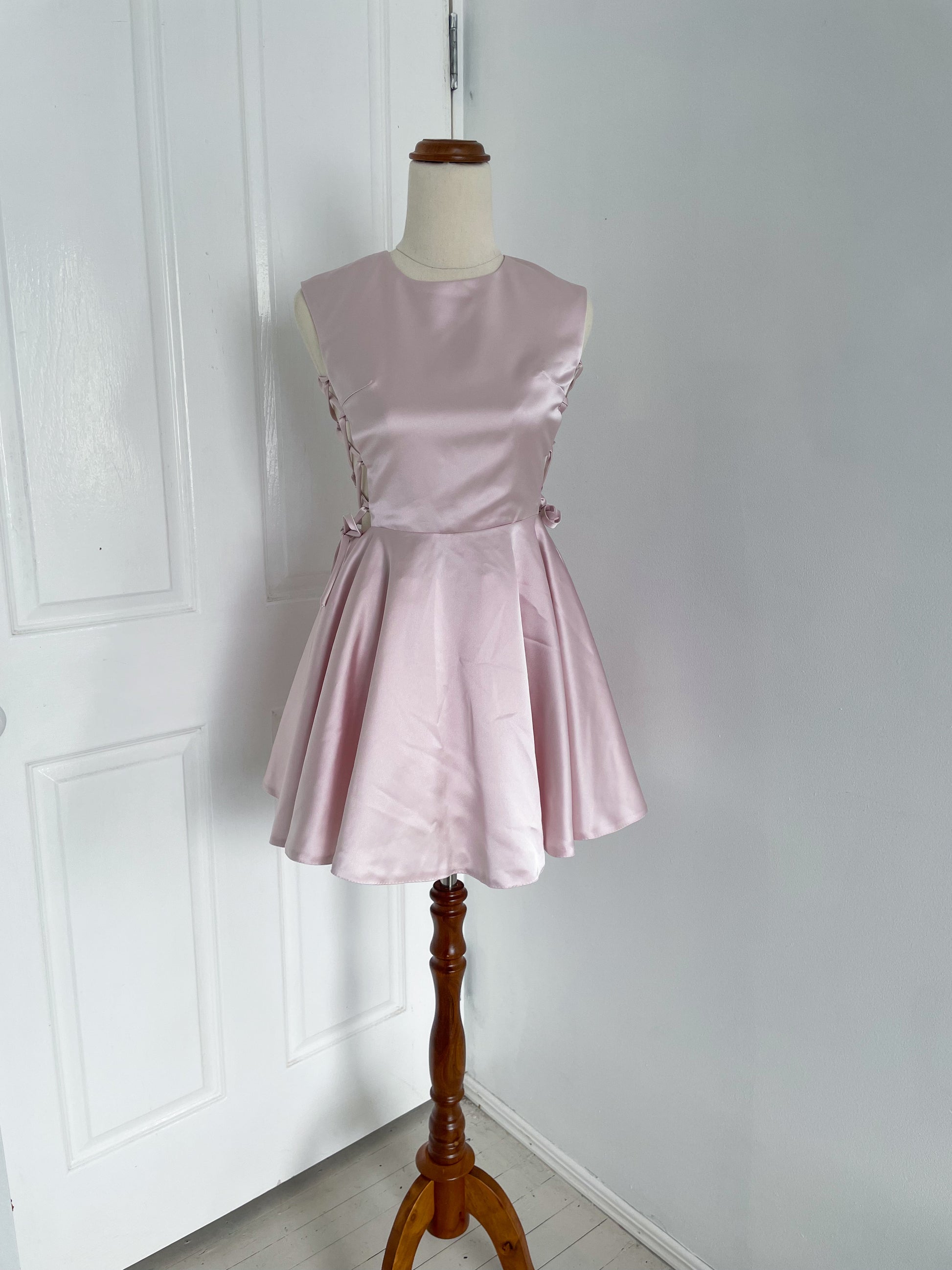 front view of A pink ballerina inspired mini dress with corset sides