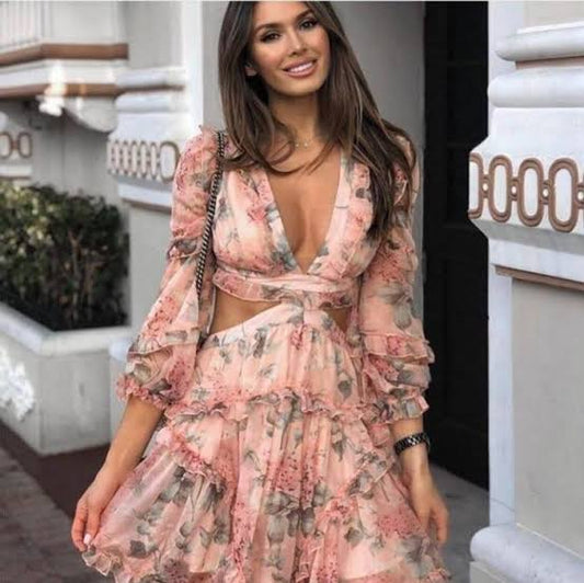 A sheer, light weight mini dress with cut out sides and ruffle detail. pink pastel in colour with sage green leaves.
