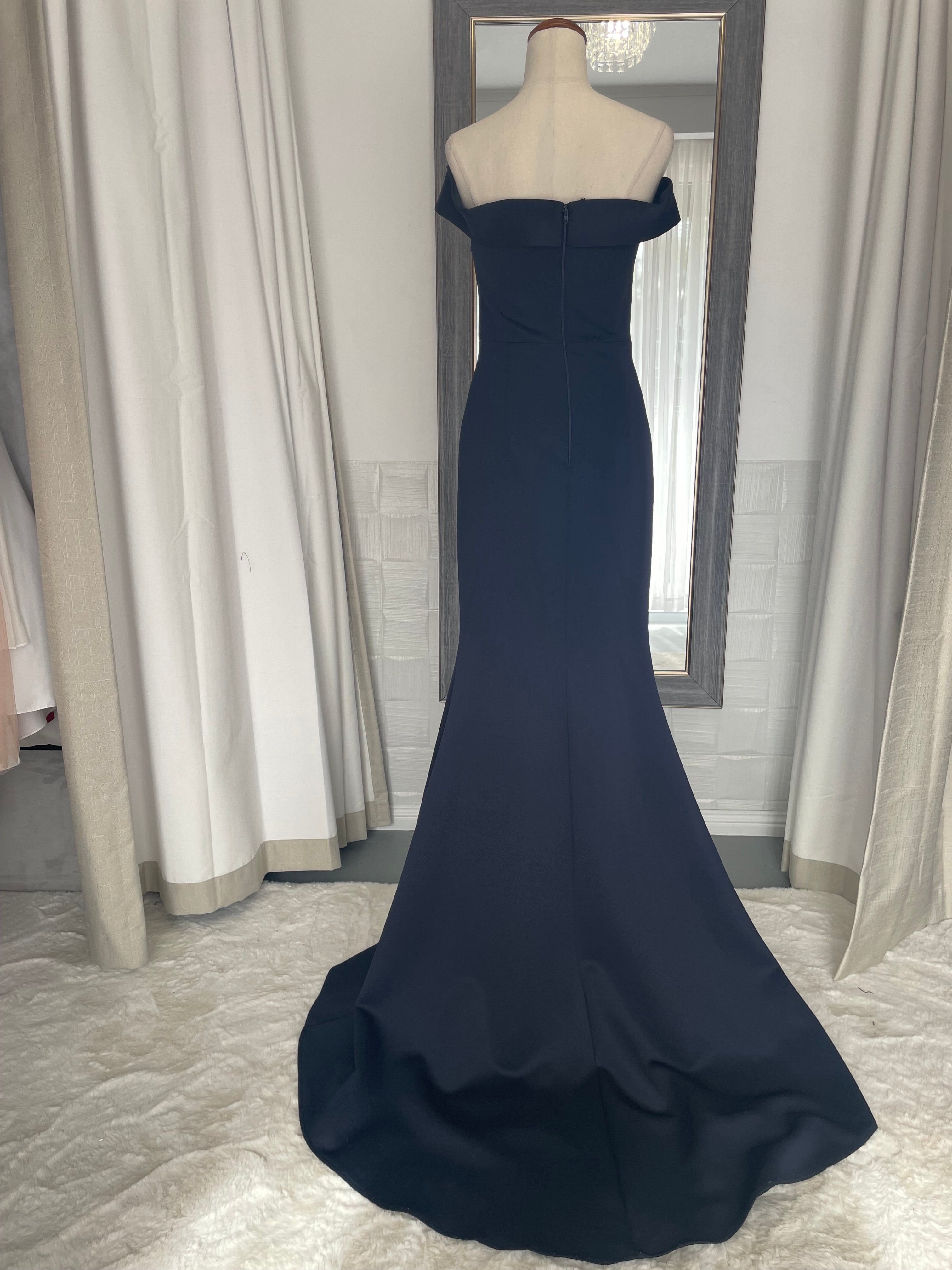back of Navy blue off the shoulder formal gown. twist front knot detail. long train and finger loop. crystal waist applique. 