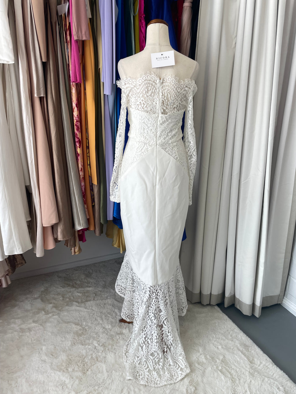 the Loretta dress features an off-shoulder scalloped neckline, delicate lace sleeves, and a flattering hi-lo mermaid hem. Crafted from smooth ponte fabric, this form-fitting design 