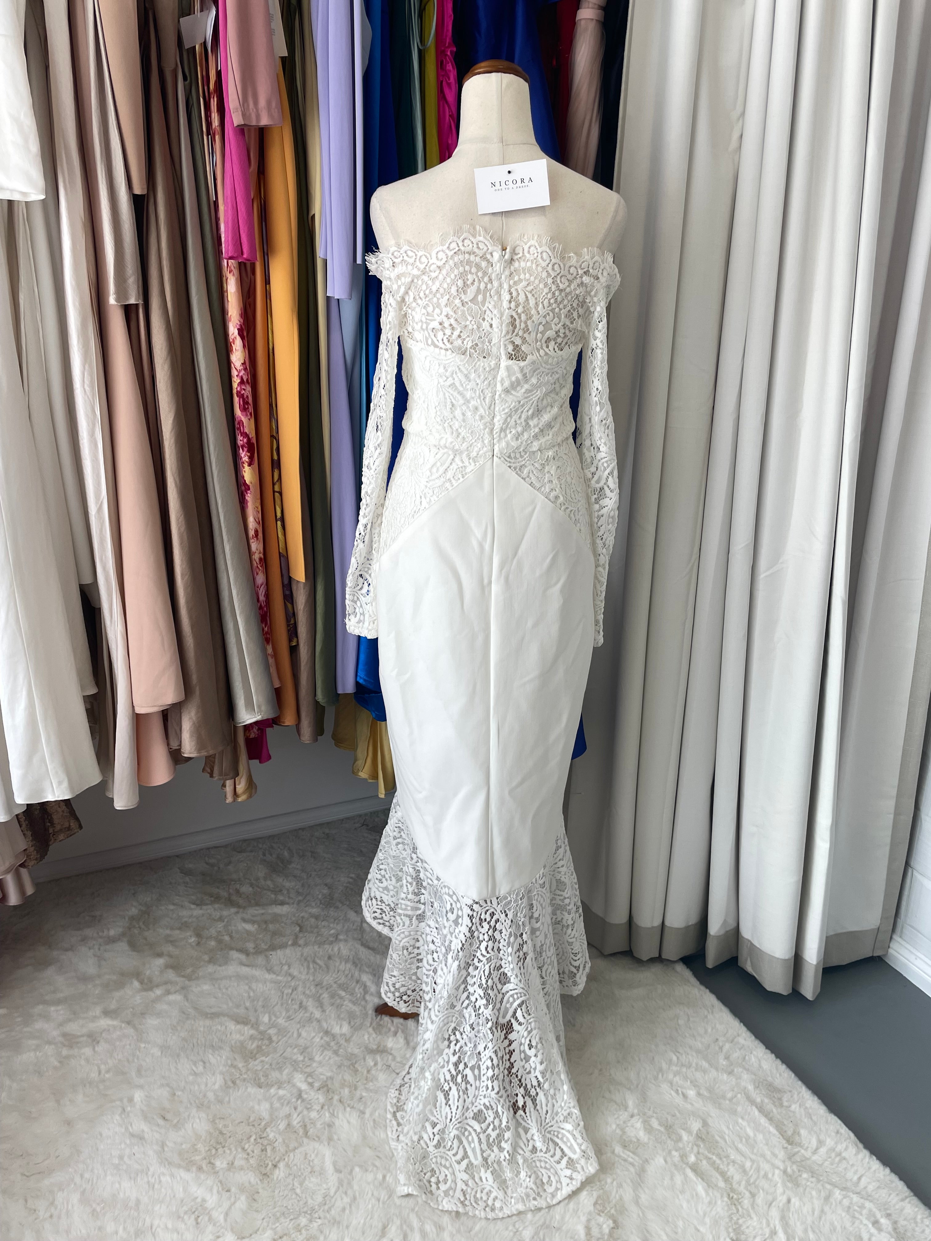 the Loretta dress features an off-shoulder scalloped neckline, delicate lace sleeves, and a flattering hi-lo mermaid hem. Crafted from smooth ponte fabric, this form-fitting design 