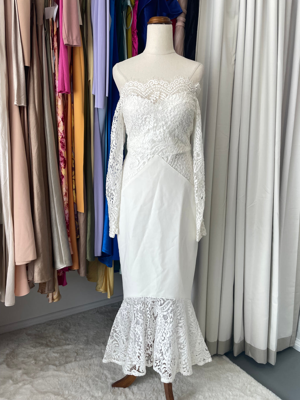 White lace dress on a mannequin. Loretta Romance dress. White lace long sleeve off the shoulder bridal reception gown with mermaid like train