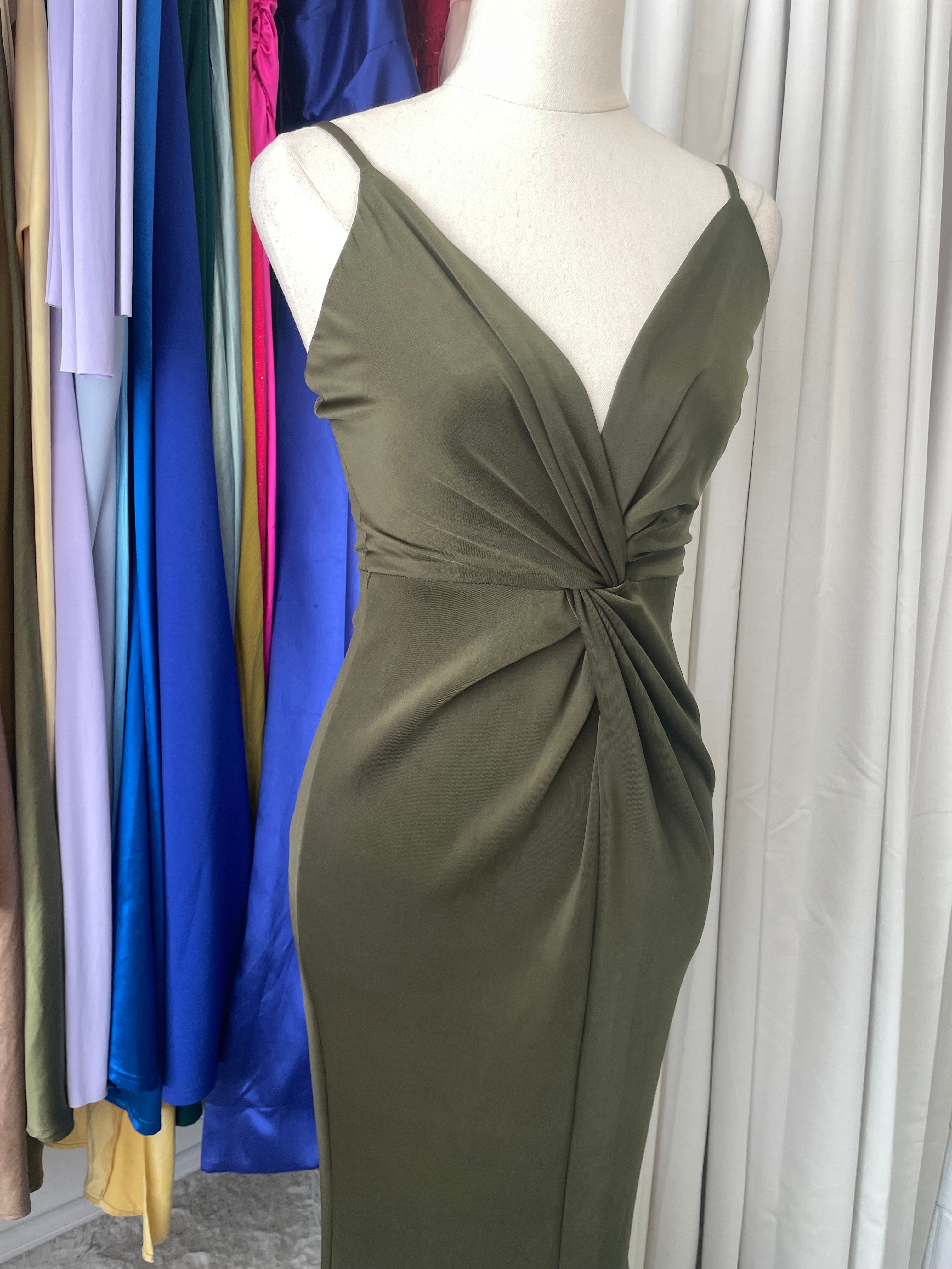 Mannequin wearing a Sheike green Gown with a knot detail on a colorful fabric background