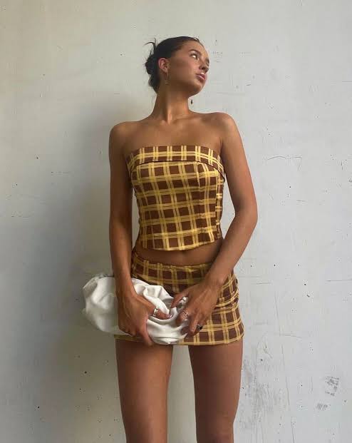 Woman wearing a checkered outfit against a plain background