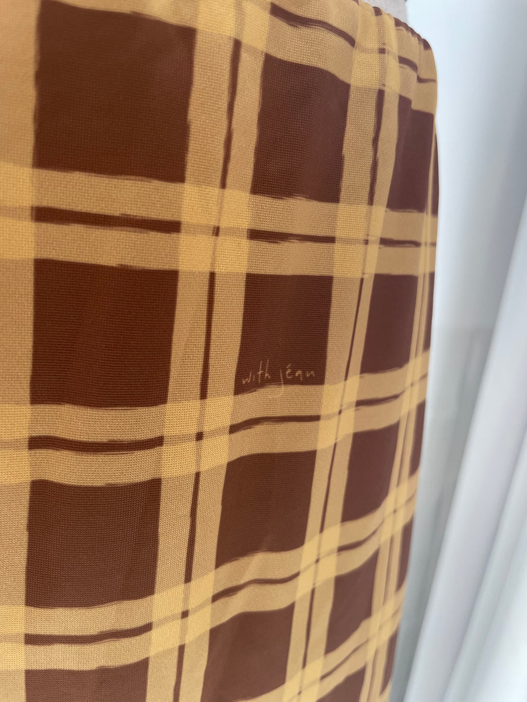 Brown and beige checkered fabric with a brand name on a white background