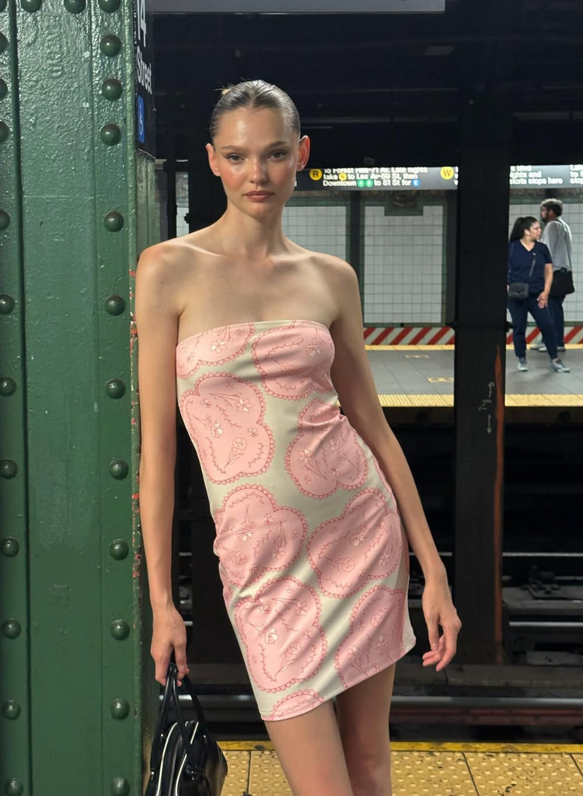 Woman in a pink dress standing in a subway station