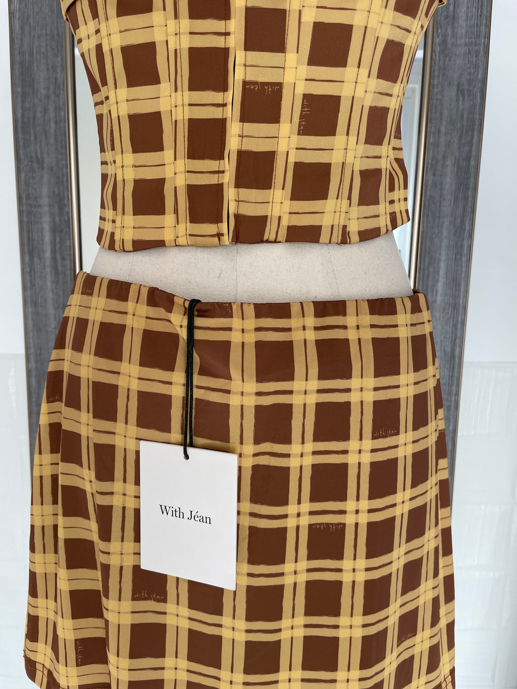 Brown and beige plaid fabric with a visible brand label on a white background